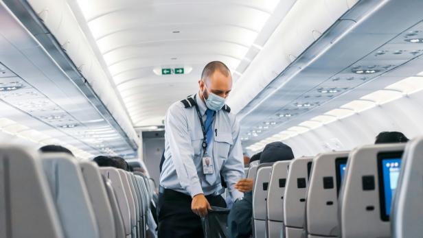Männliches Crew-Mitglied eines Flugzeugs geht durch die Reihen
