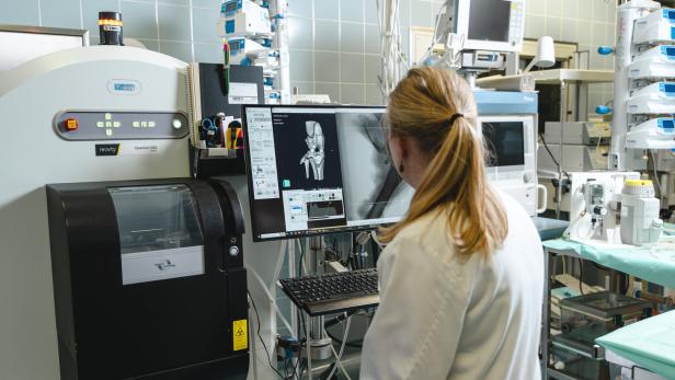 Szene aus einem Labor, eine Wissenschafterin blickt auf eine Röntgenaufnahme eines Kniegelenks: Forschung zu neuen Verfahren für Knie-OPs ist ein Bereich des Boltzmann-Instituts für Traumatologie.