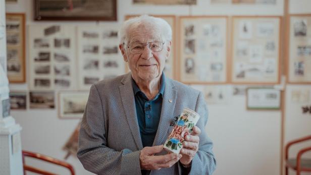 Ein Mann steht vor einer Wand mit schwarz-weiß Bildern