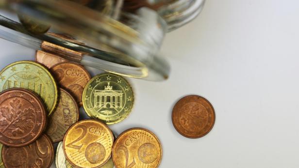 Auf dem Bild sieht man einen umgelegten Glasbehälter aus dem einige Euro- und Centmünzen herausfallen