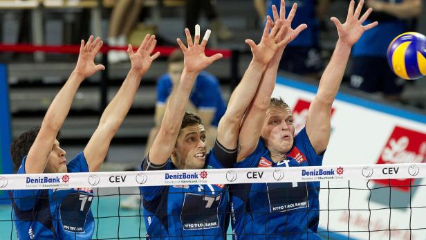 Volleyballspieler versuchen, einen Ball über das Netz zu schlagen.