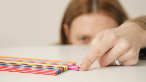 Frau, die einen Stift verschiebt, damit er optisch gleich aufgereiht ist, wie die anderen