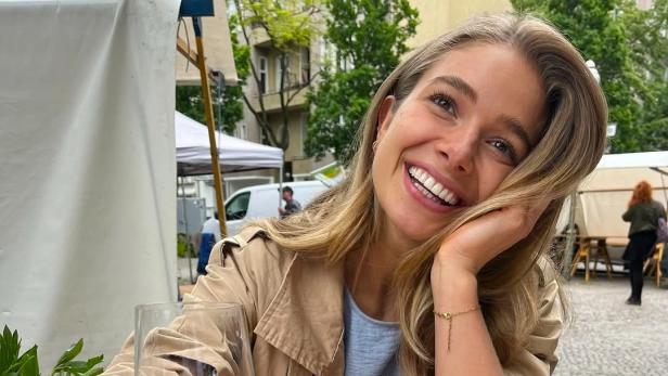 Lola Weippert stützt ihren Kopf auf der Hand ab und lacht in die Kamera