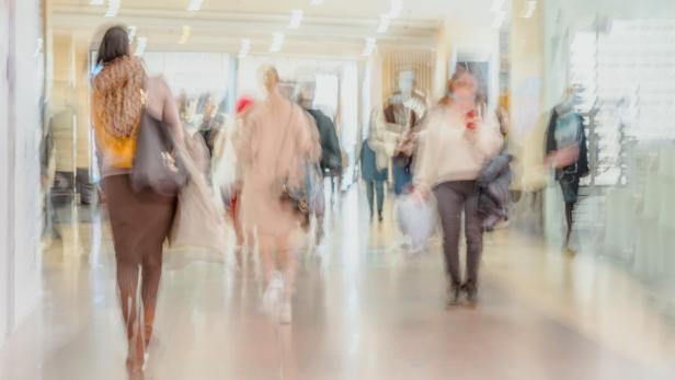 Abstract defocused motion blurred people walking in shopping mall center, urban lifestyle, consumerism concept.