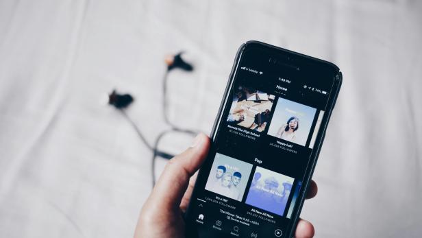 Handy mit verschiedenen Songs auf Spotify auf dem Display