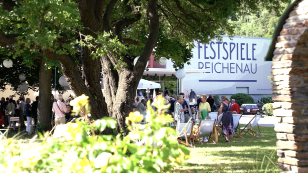 Außenbereich der Festspiele Reichenau, Veranstaltung mit Stühlen im Grünen zwischen Bäumen 
