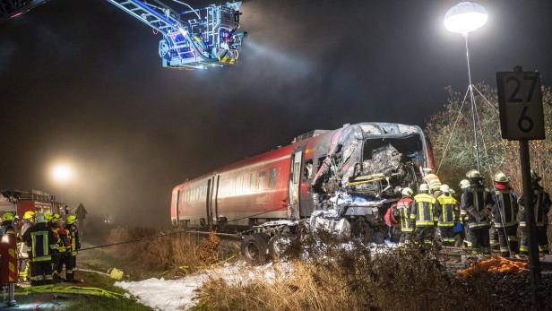 Ein verunglückter Zug, umgeben von Feuerwehrleuten und Rettungskräften bei Nacht.