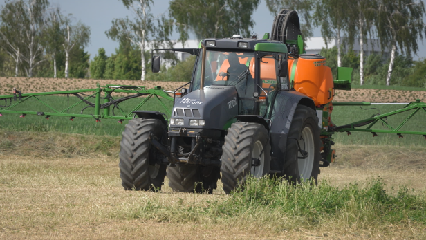 Ein Traktor mit Sprühgerät behandelt ein Feld mit Pflanzenschutzmitteln.