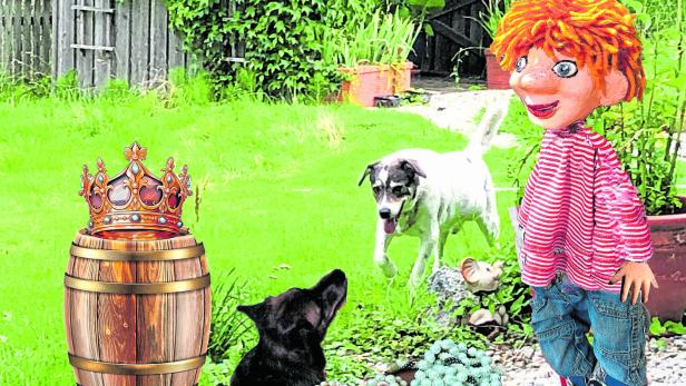 Die Puppe Seppy steht mit zwei Hunden, einer Krone und Schmuck im Garten.