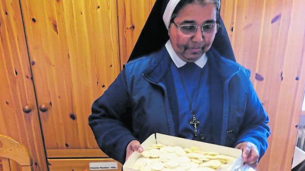 Eine Nonne hält eine Schachtel mit Hostien in der Hand.
