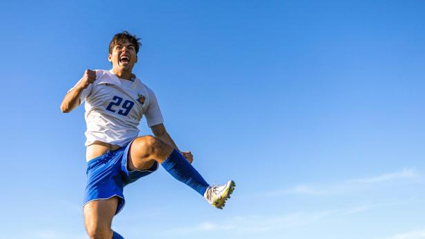 Ein Fußballspieler springt in die Luft vor Freude.