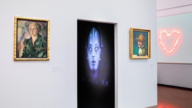  Ein Ausstellungsraum mit Bildern, Filmausschnitten und Kunstwerken.