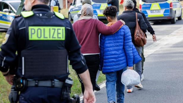 Ein Polizist geht hinter Migranten hinterher