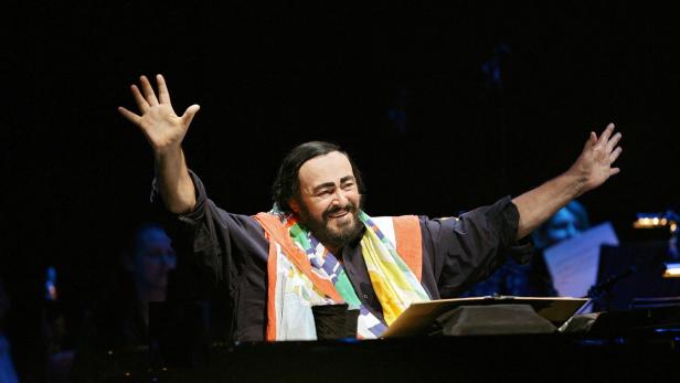 Luciano Pavarotti mit erhobenen Armen während eines Auftritts.