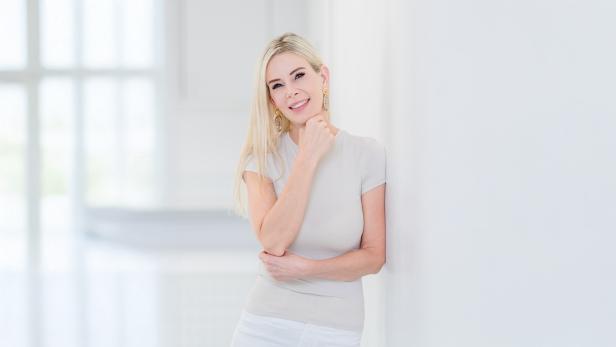 Eine Frau in einem weißen T-Shirt vor einer weißen Wand. 