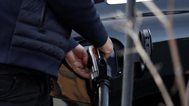 Mensch führt Ladestecker in ein Elektroauto ein.