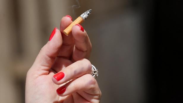 FILE PHOTO: A woman smokes in the public space Eine Frau hält eine brennende Zigarette in der Hand