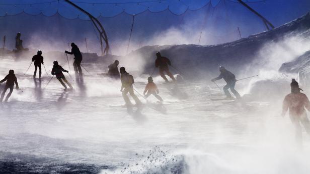 Many skiers silhouettes over sunset light