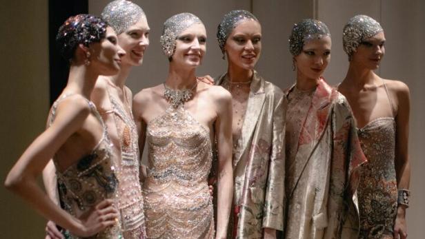 Eine Gruppe von Frauen in glitzernden Kleidern und Kopfbedeckungen posiert für ein Foto.