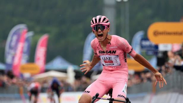 Ein Radrennfahrer in rosa Trikot jubelt über seinen Sieg beim Giro d'Italia.