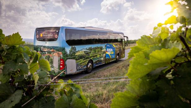 Ein Bus mit Werbung für das Burgenland fährt durch eine ländliche Gegend.