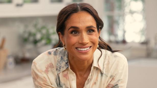 Ein Porträt von Herzogin Meghan in einem floralen Hemd, lächelnd.