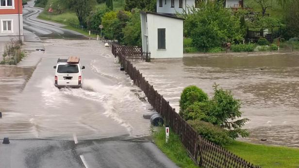 Auto fährt auf überfluteter Fahrbahn