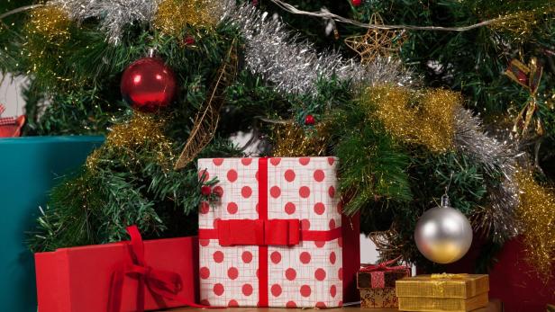 Geschmückter Christbaum mit eingepackten und schön dekorierten Geschenken.