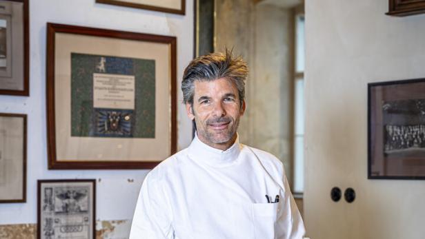 Ein Mann im weißen Kittel präsentiert ein Skizzenbuch mit Schuhdesign von Maßschuhe Scheer.