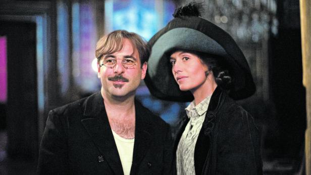 Ein Mann mit Brille und Schnurrbart und eine Frau mit Hut stehen nebeneinander.