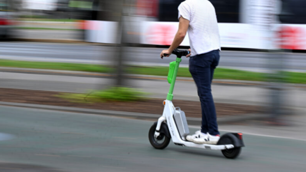 Ein Mann fährt auf einem E-Scooter durch die Stadt.