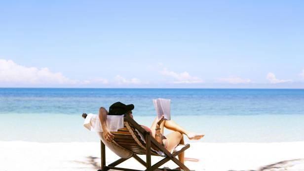 Eine Frau liest an einem Strand ein Buch