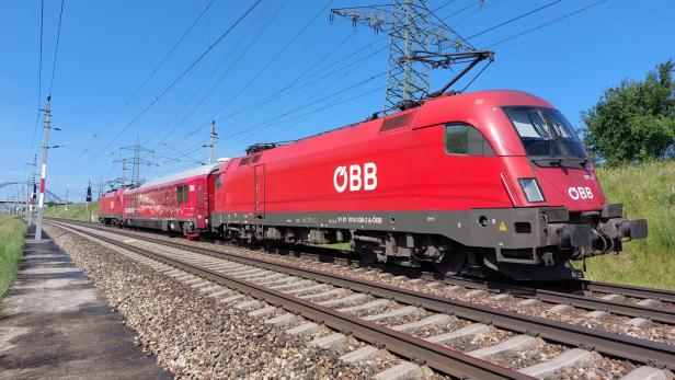 Ein roter ÖBB-Zug ist auf den Gleisen unterwegs.
