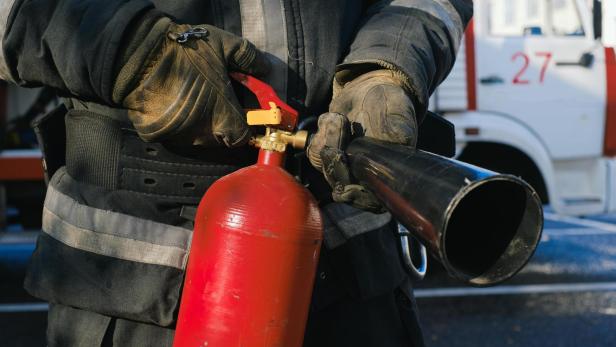 Feuerwehrmann hält Feuerlöscher in der Hand