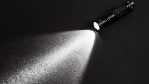 Taschenlampe mit Lichtkegel am Asphalt