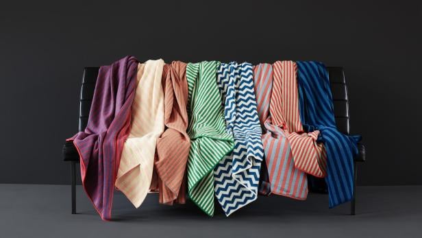 Mehrere bunte Decken hängen über einer schwarzen Bank.