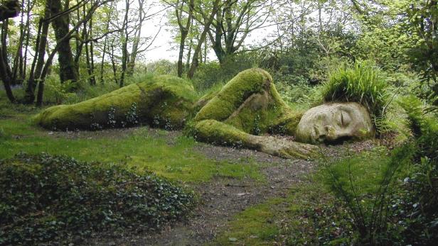 Eine moosbewachsene Skulptur einer liegenden Frau in den Heligan Gardens.