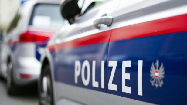 Zwei österreichische Polizeiautos mit blau-rotem Streifen und dem Wort „Polizei“ nebeneinander geparkt.