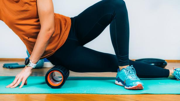Woman Using Foam Roller Massager at Home.