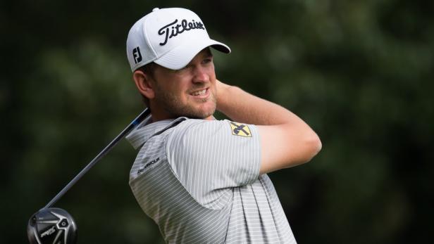 Ein Mann mit einer „Titleist“-Kappe schwingt einen Golfschläger.