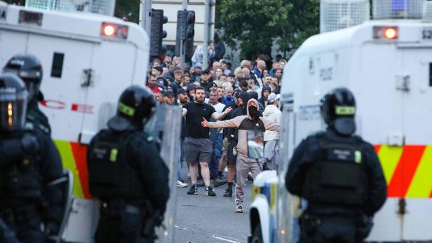 Polizisten stehen vor einer Menschenmenge während einer Unruhe in Nordirland.