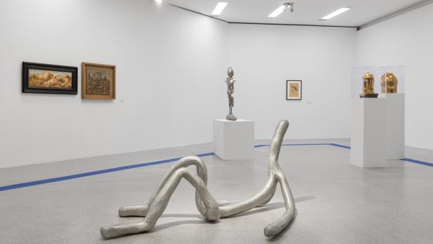 Eine Skulptur aus Metall liegt auf dem Boden einer Kunstausstellung.