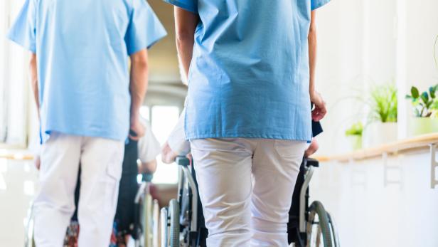 Midsection Of Nurses Pushing Wheelchairs