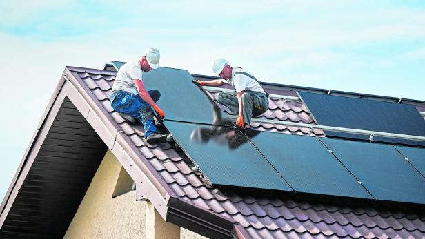 Workers building solar panel system on roof of house. Men installing photovoltaic solar module