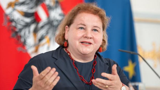 Sozialministerin Korinna Schumann bei einer Pressekonferenz im Bundeskanzleramt vor einer Fahne von Österreich und der EU 