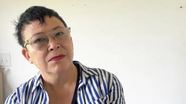 Eine Frau mit Brille und gestreiftem Hemd blickt in die Kamera.