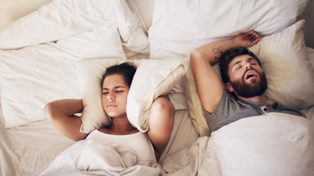 Mann schnarcht im Bett.