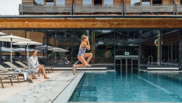 Ein Kind springt in einen Pool vor einem Hotel.