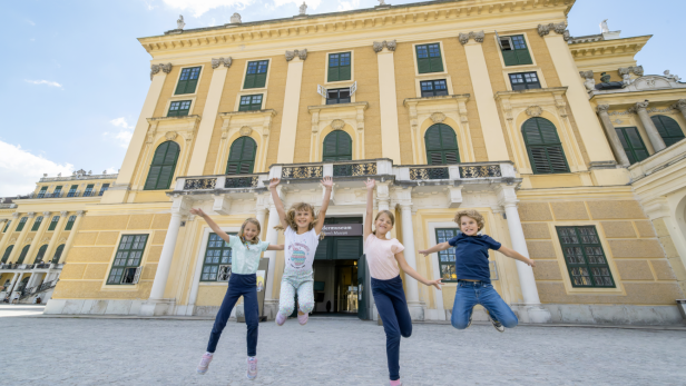 Vier Kinder vorm Schloss Schönbrunn. 