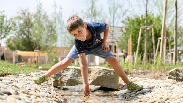 Ein Junge spielt in einem Wasserlauf. 